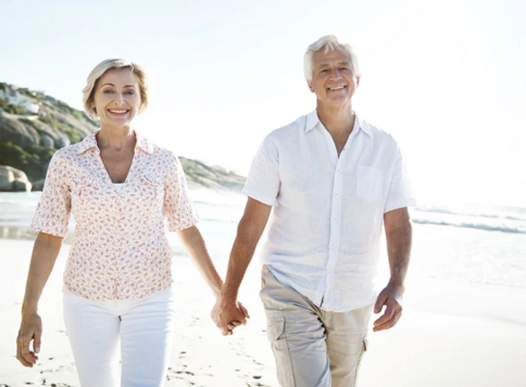 Seniors Couple Holding Hands and Walking On Beach
