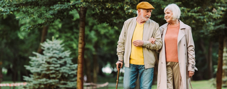 Senior father and his young son sitting on bench by lake in nature, talking.